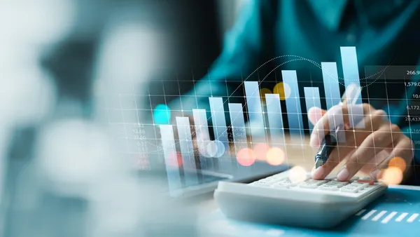 Hand typing on a calculator next to a graph
