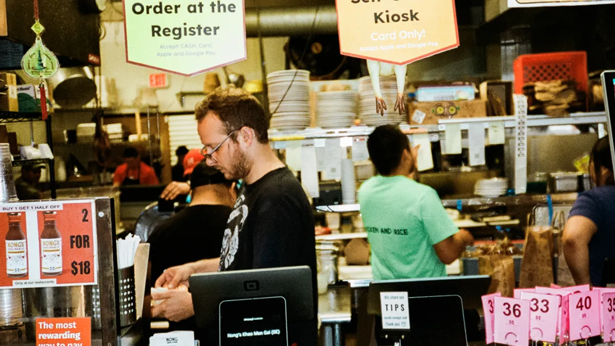 Three people working in a kictchen with 2 Square Kiosks visible.