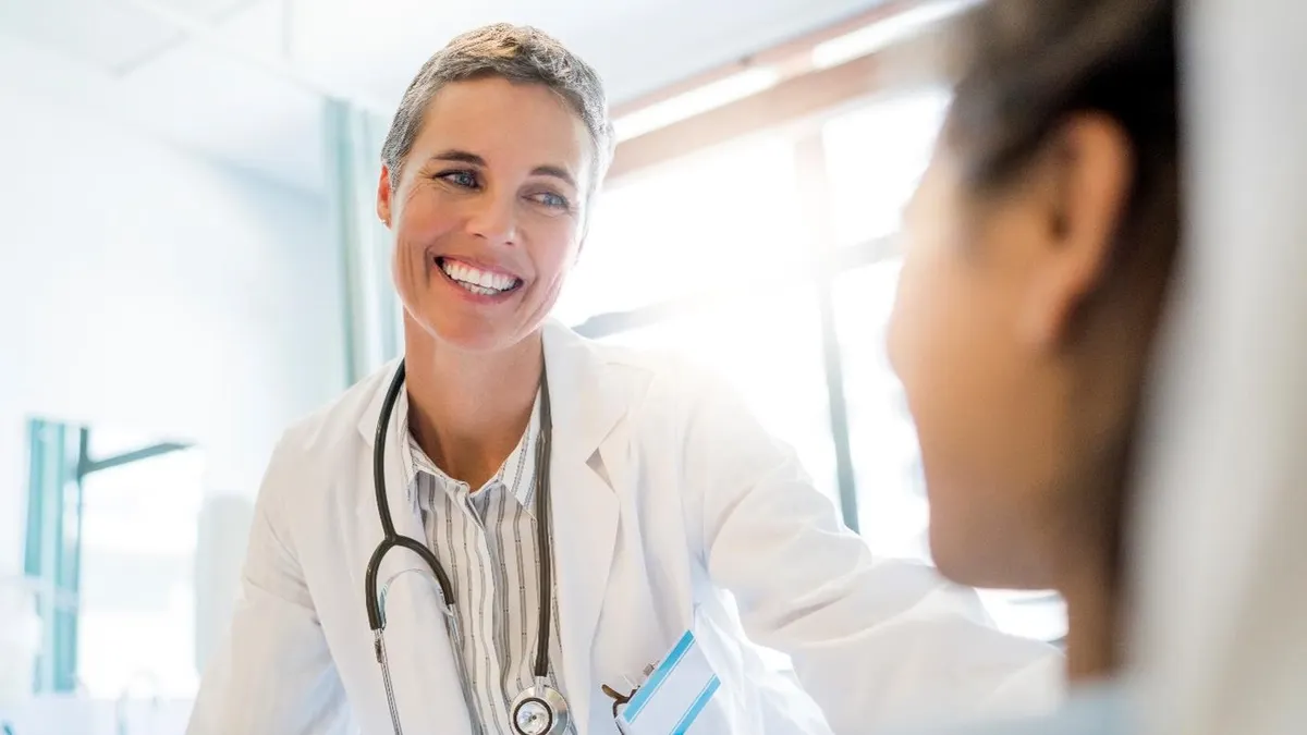 Smiling doctor looking at female patient in ward.