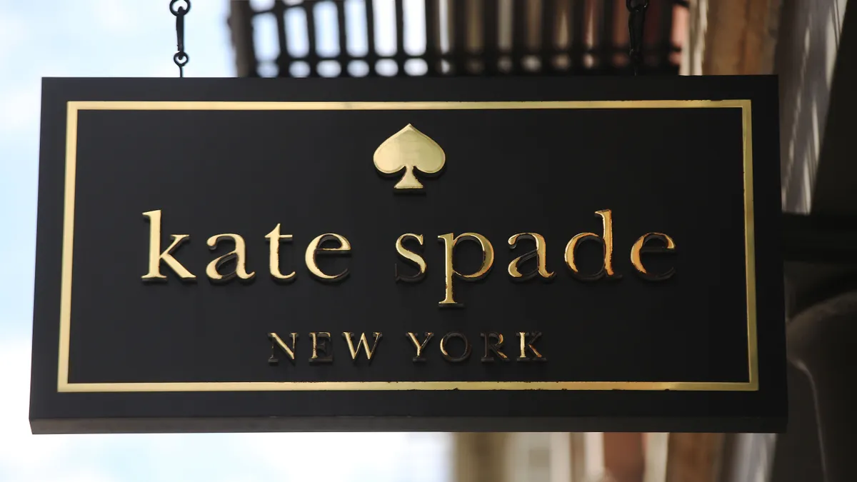 A close up of a Kate Spade New York sign hanging above a store front.