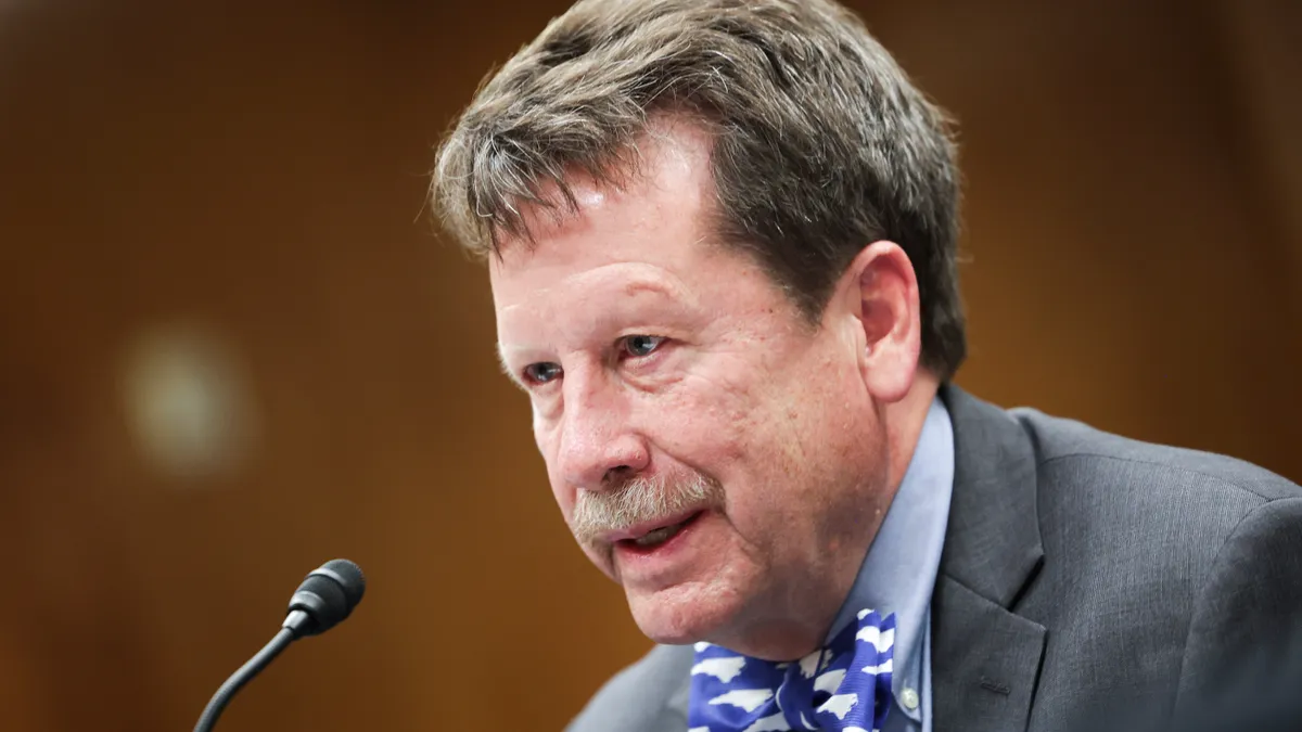 A man speaks in front of a microphone at a hearing.