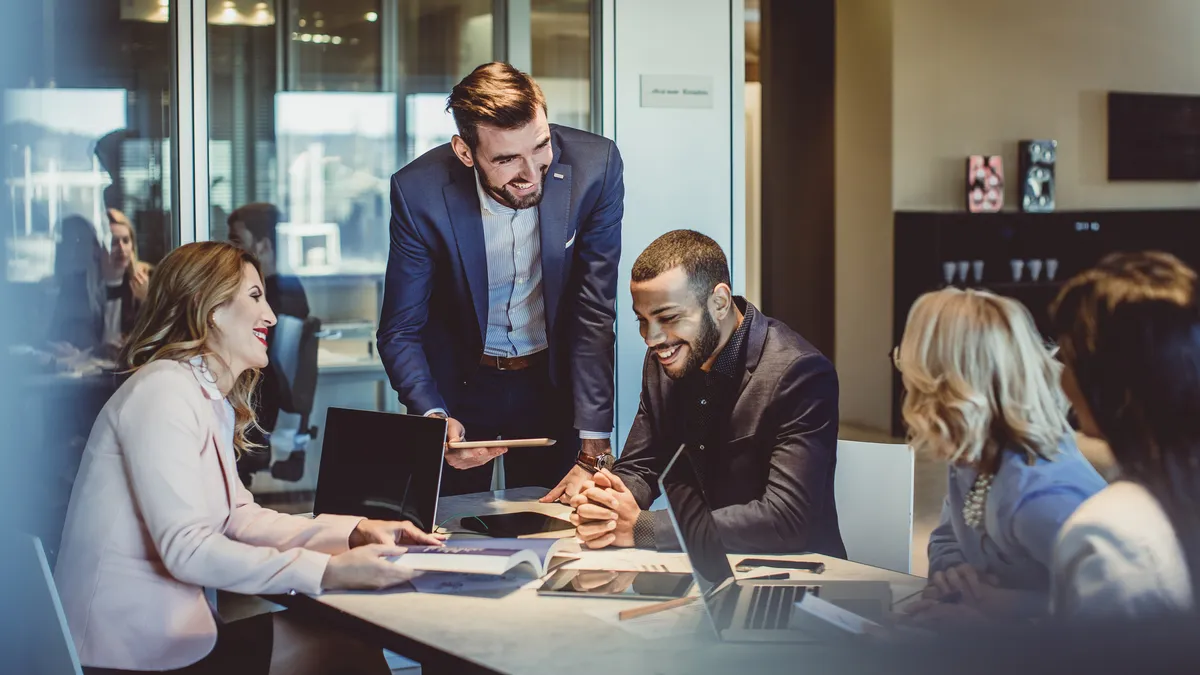 A picture of four business people having a meeting at a table in a casual corporate office setting.