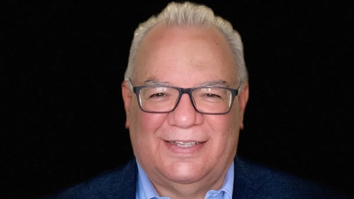 An image of a person smiling wearing a blue suit