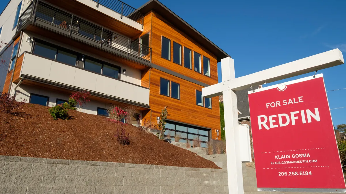 A Redfin real estate yard sign stands in front of a house in Seattle.