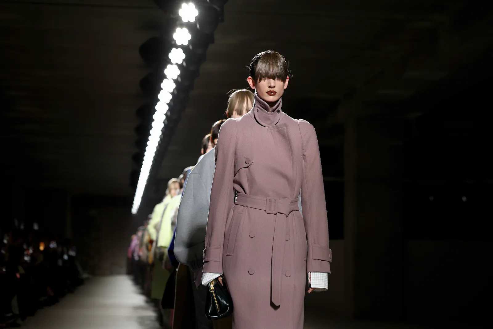 Models wear coats and walk down a runway.