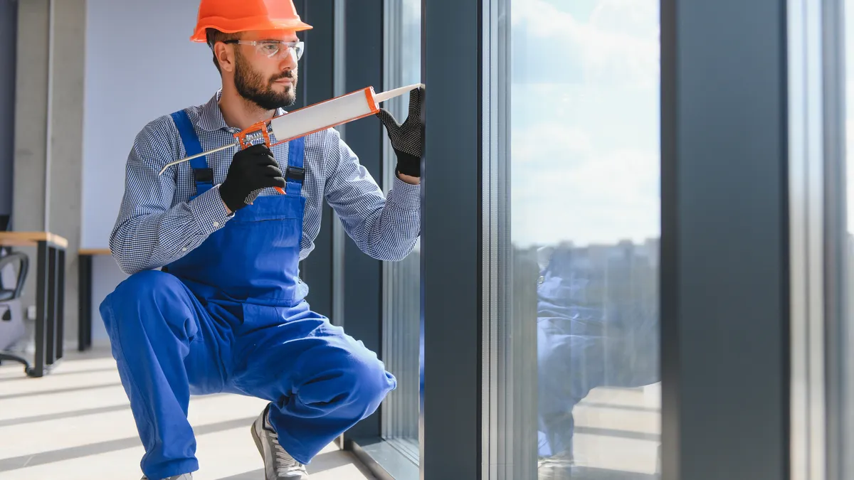 A worker installs a plastic window indoors