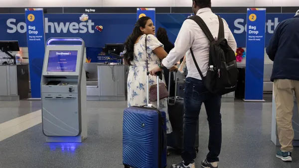 People wait in line to check in for flights with their luggage.