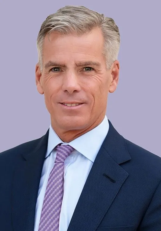 A person wearing a suit and tie smiles for a photo