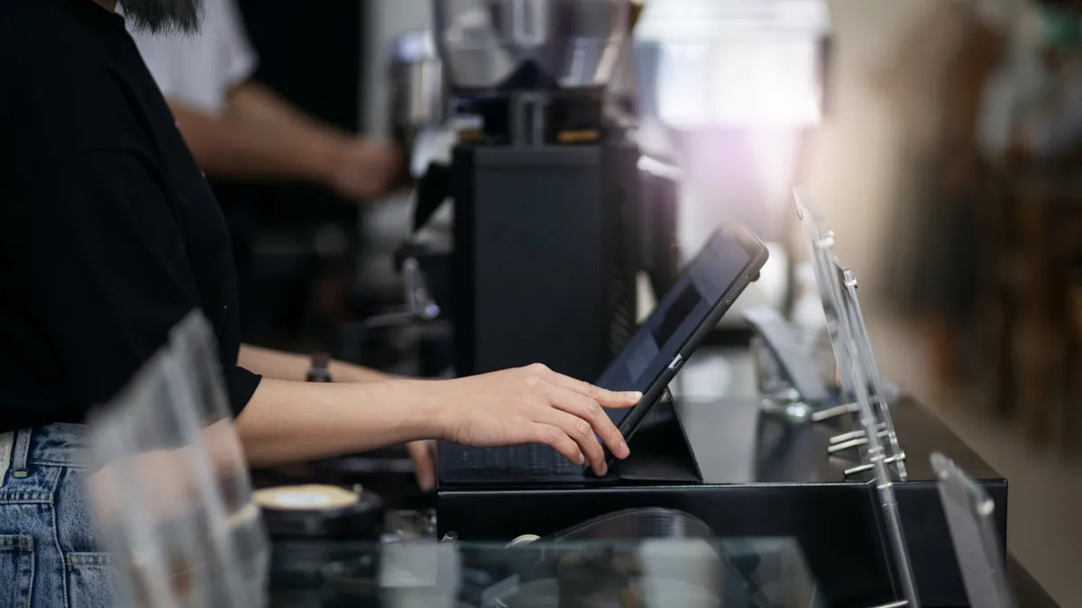 Worker using point of sale system in coffee shop