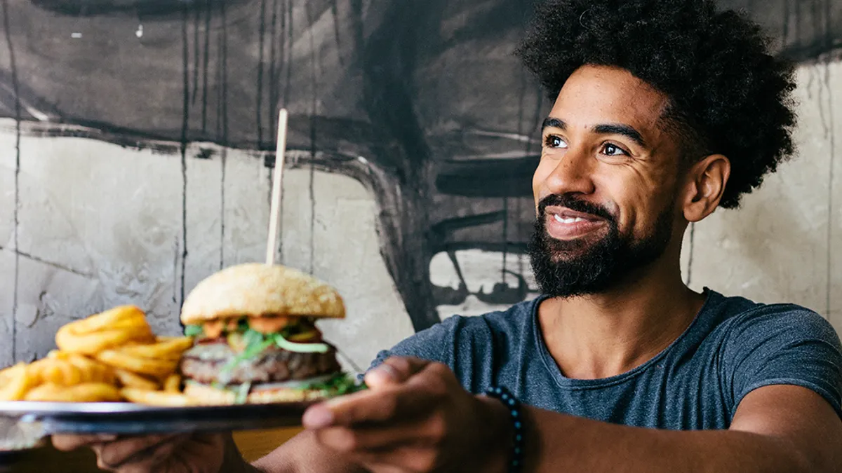 Person holding out plate with burger and fries