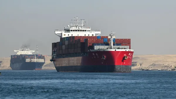 Two cargo ships transit on water through the Suez Canal