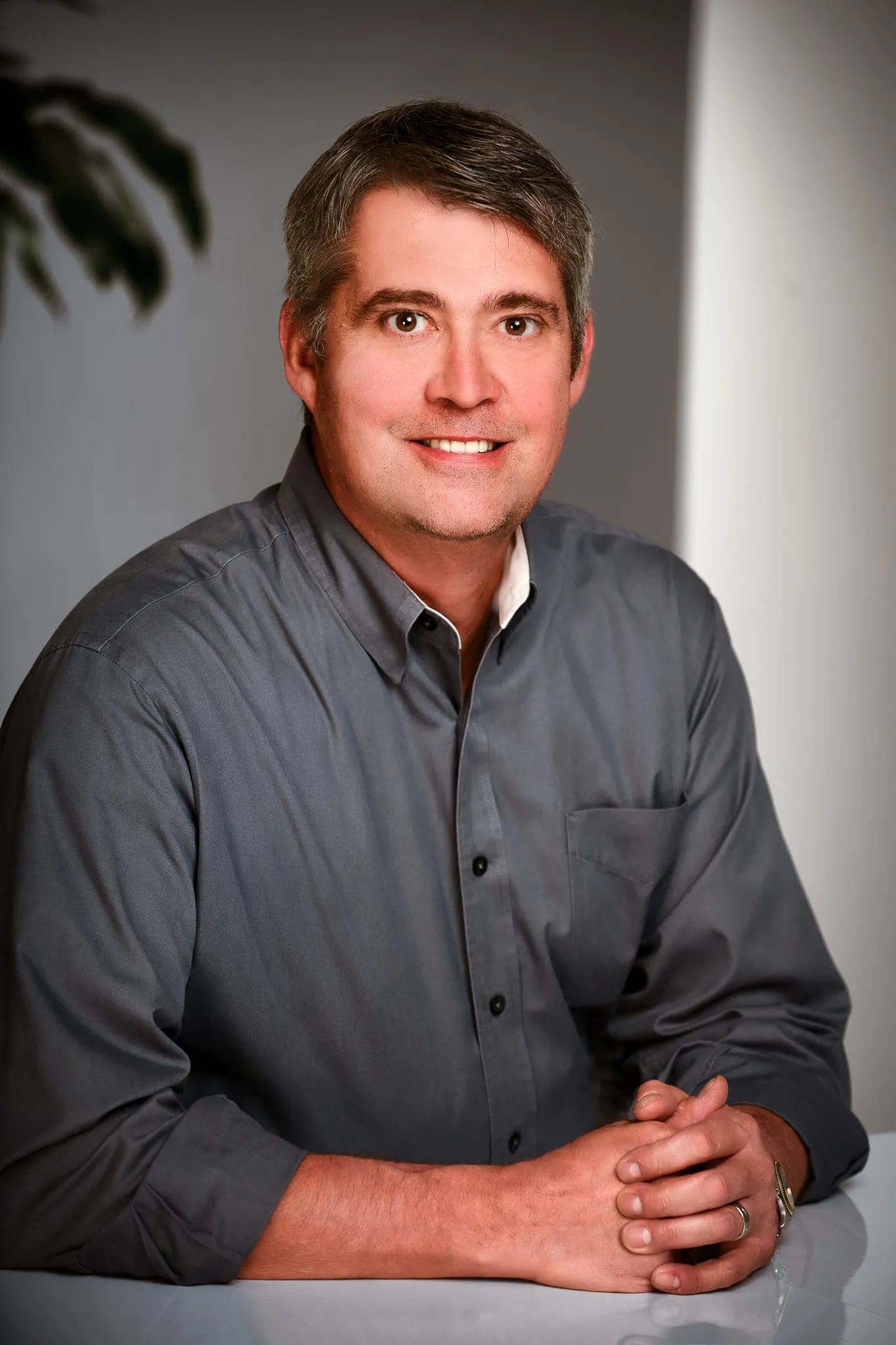 Man in button down shirt sitting with hands clasped