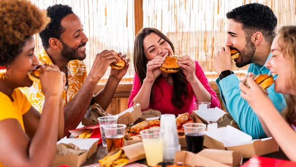 An image of several people eating hamburgers and french fries from a generic fast food restaurant.