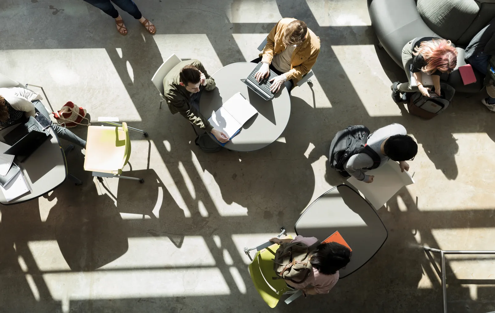 Aerial shot of college students working at tables in a sunny room