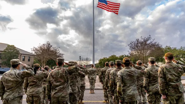 Members of an Air Force unit in combat uniform salute during a flag ceremony