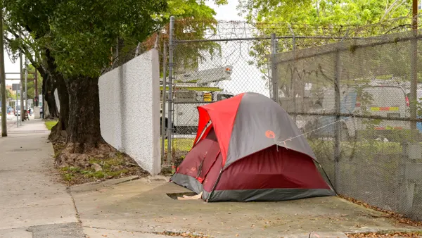 A red tent next to a chain link fence with barbed wire on top.