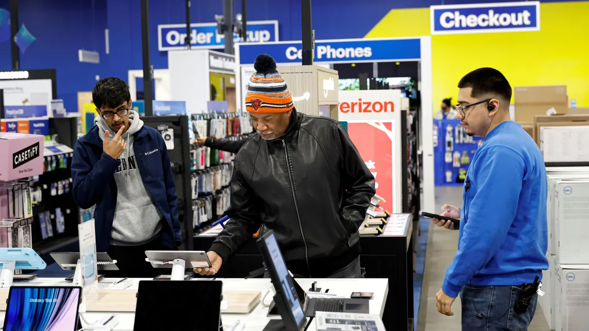 Customers browse at a Best Buy, while an associate stands nearby ready to help.