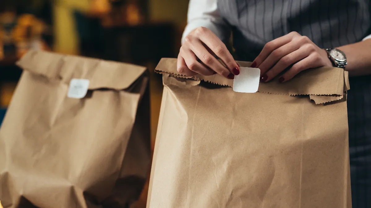 An image of a woman preparing bags for takeout in a restaurant