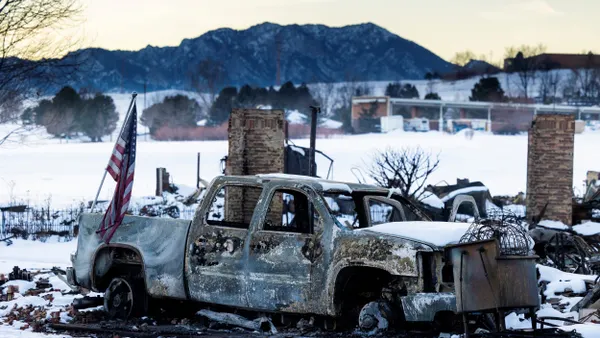 An American flag is shown affixed to a burned truck