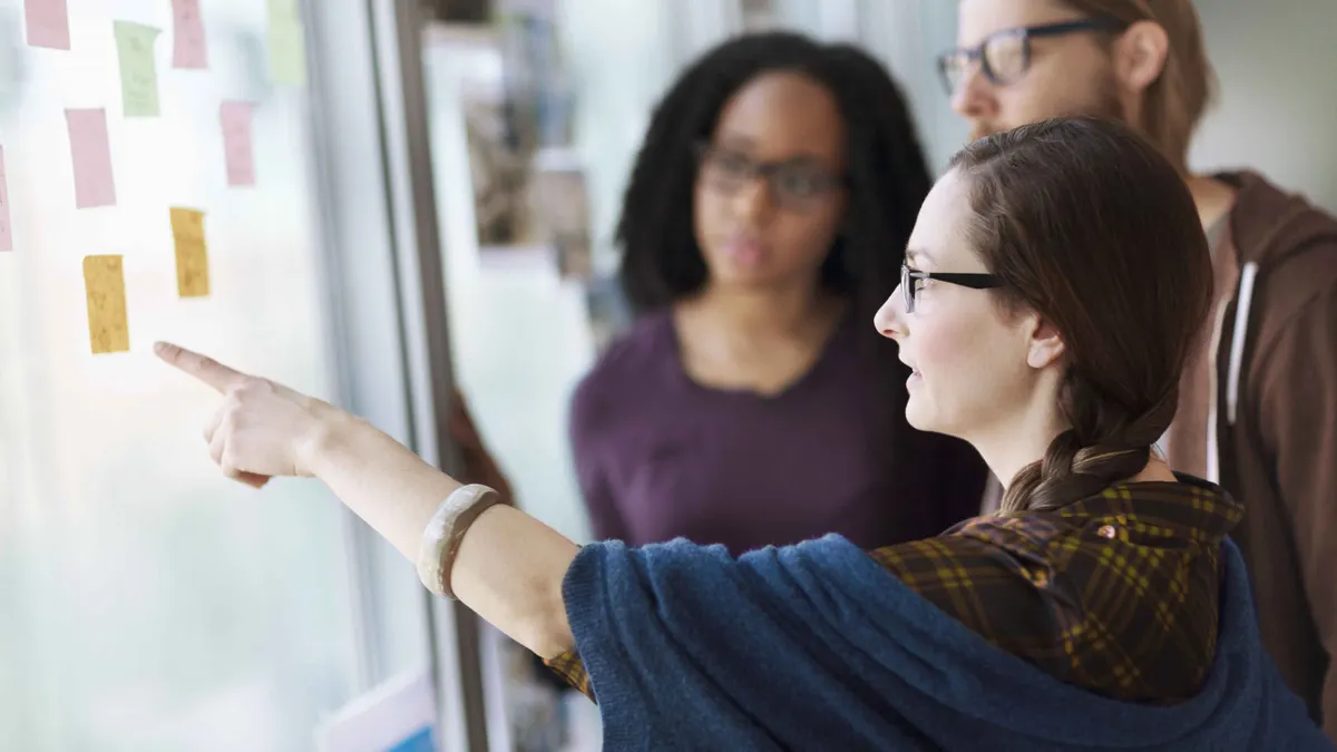 Creative colleagues reviewing ideas on wall in studio office stock photo