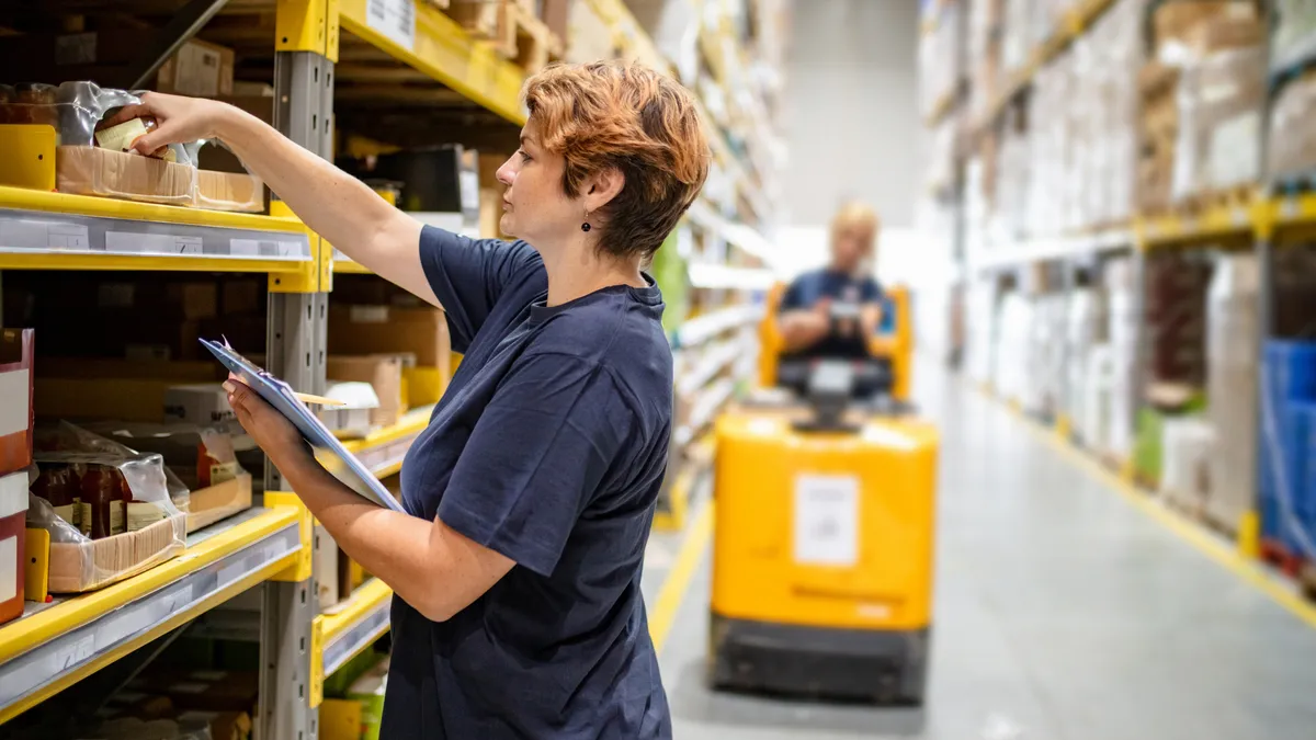 Woman checking packages on warehouse racks