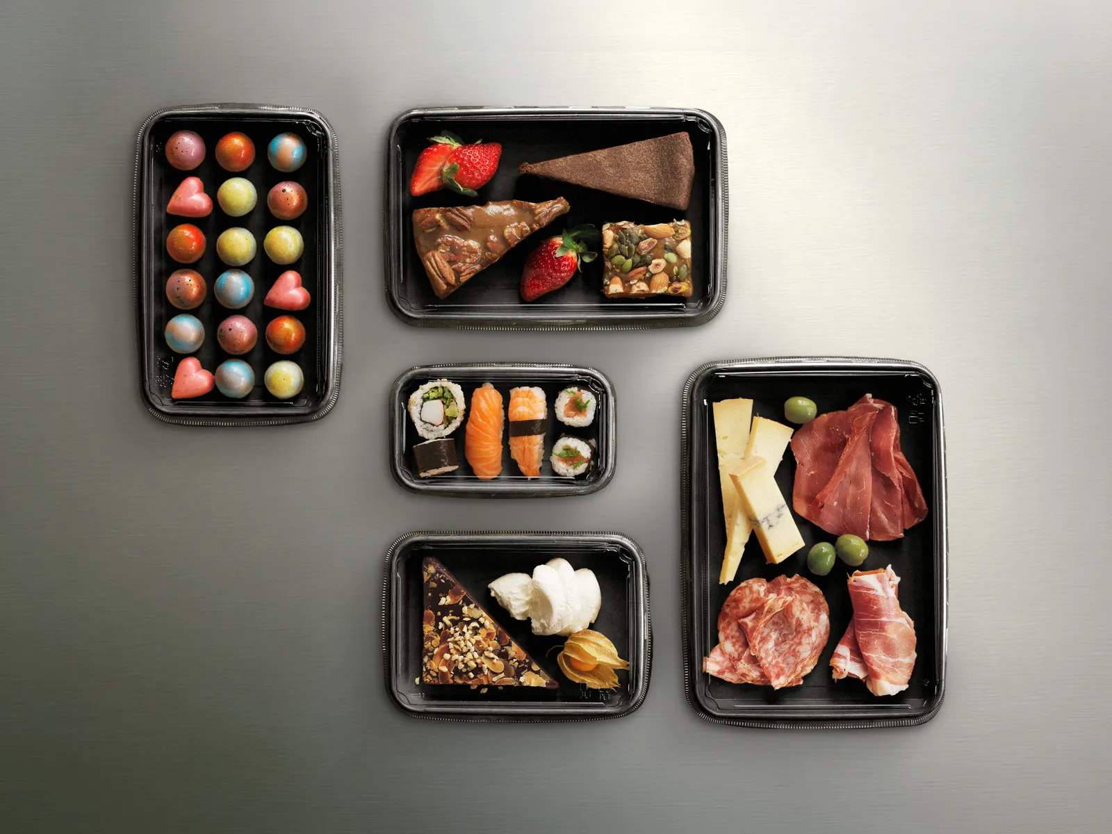 A variety of foods displayed inside black foodservice containers.