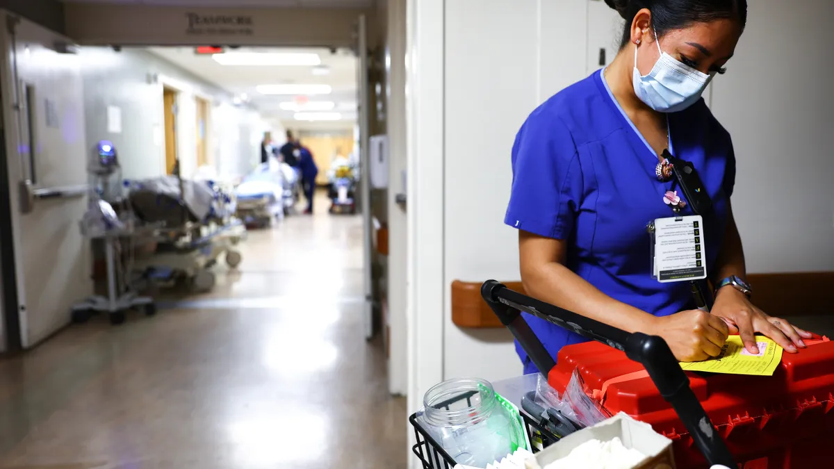 A person in scrubs writes on a pad.