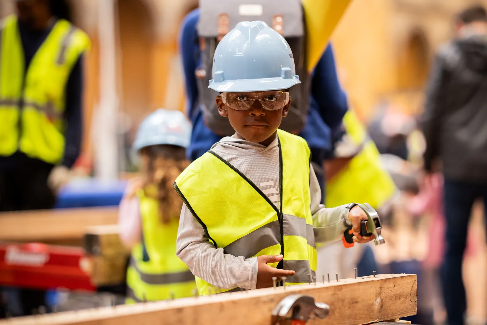 A child poses with a hammer and nails.