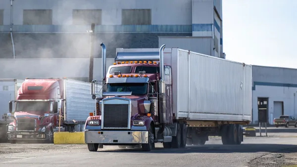 Trucks in an industrial setting by a building.