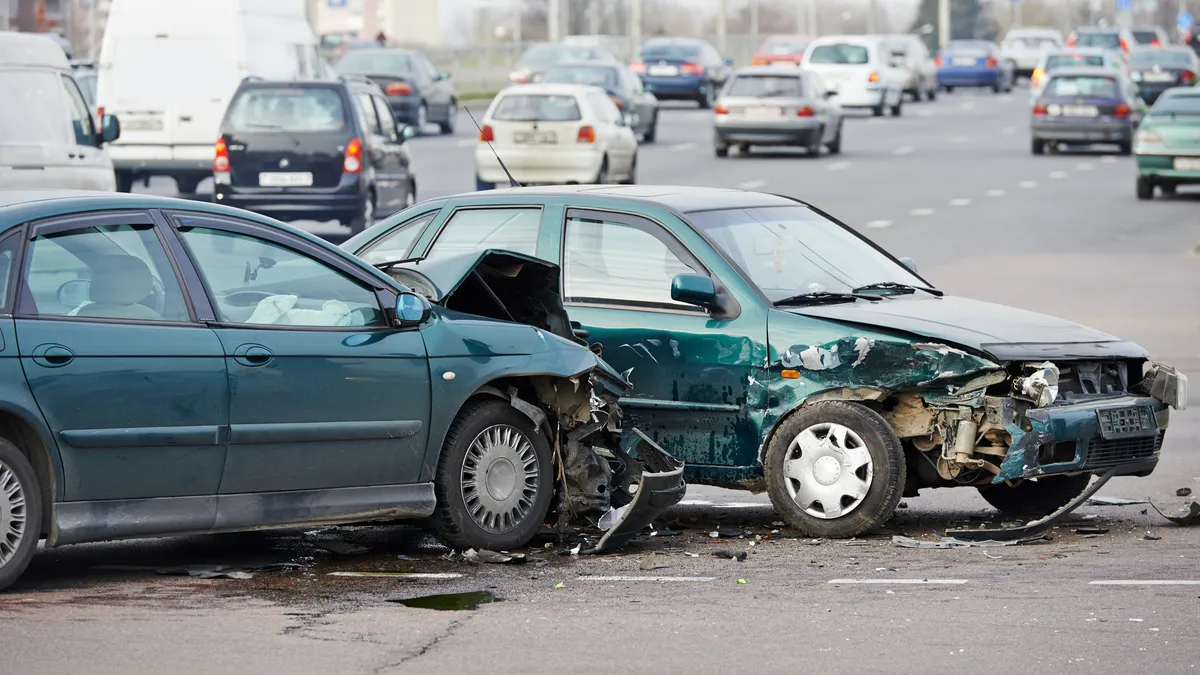 Two cars in a collision with damage to the front and side on a multi-lane road.