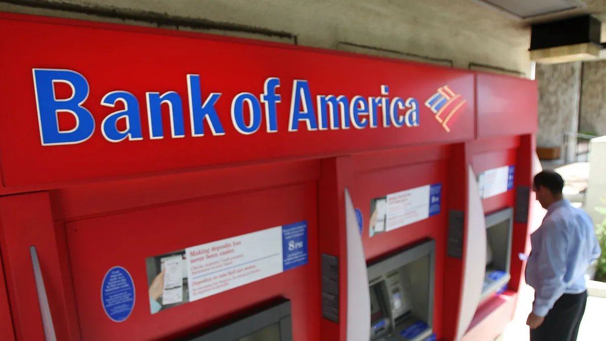 A person uses a red Bank of America ATM.