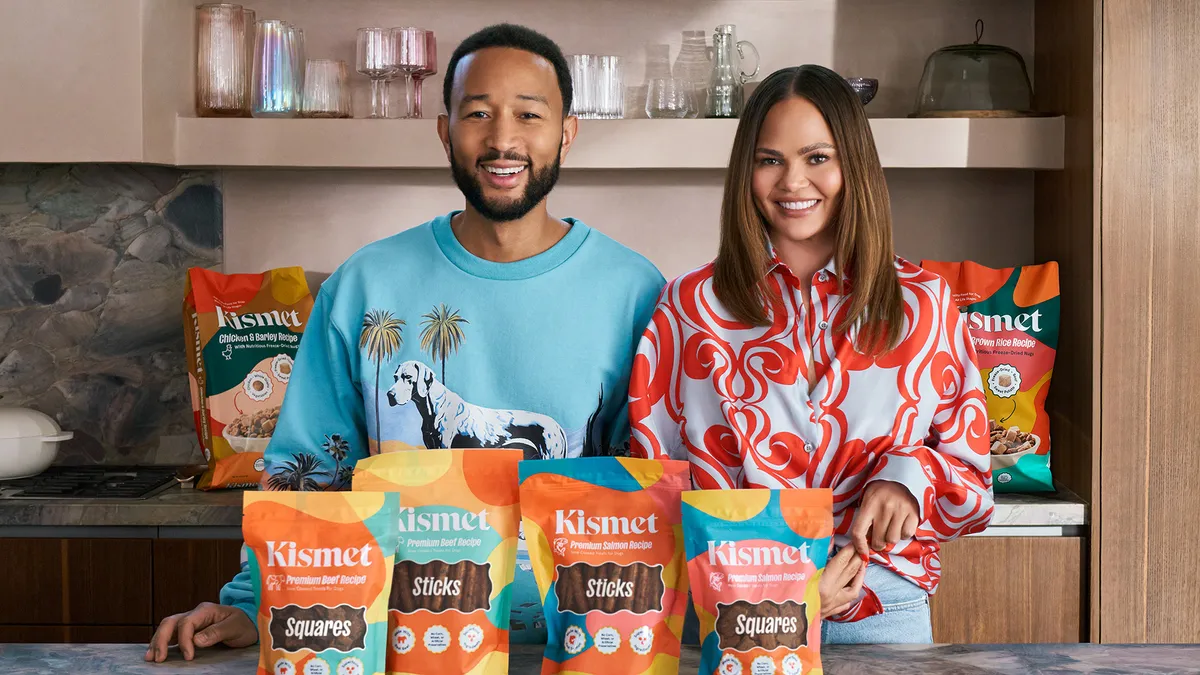 Chrissy Teigan and John Legend stand near Kismet pet brand products