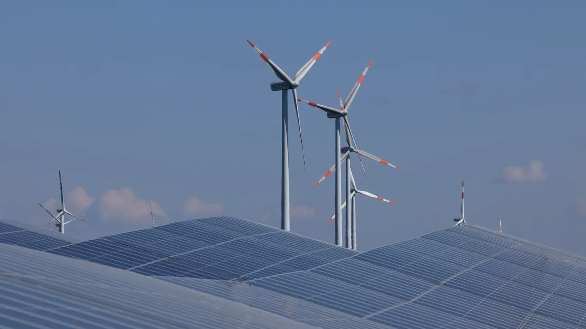 Newly-installed solar panels face the sky at the construction site of a new solar energy park as wind turbines spin behind in Germany.