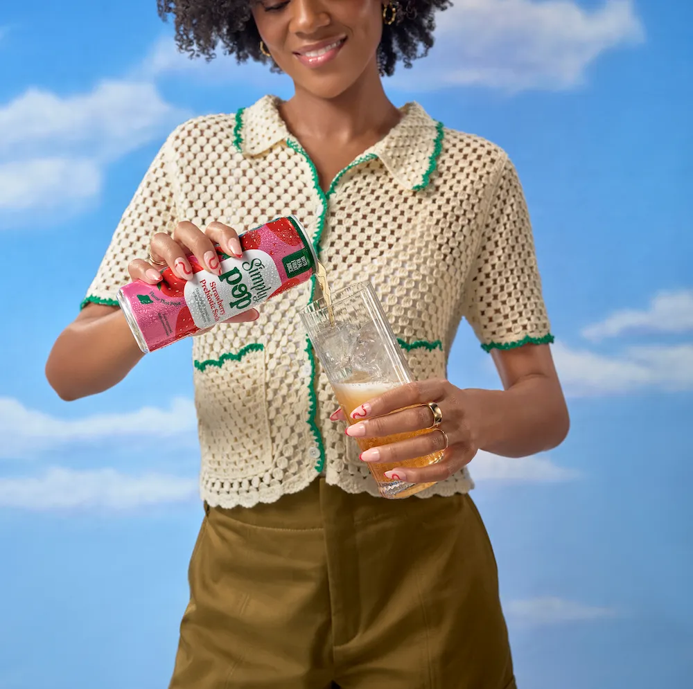 A woman pours a can of Simply Pop