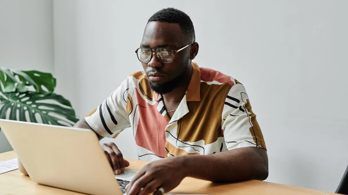 A Black person types on a laptop