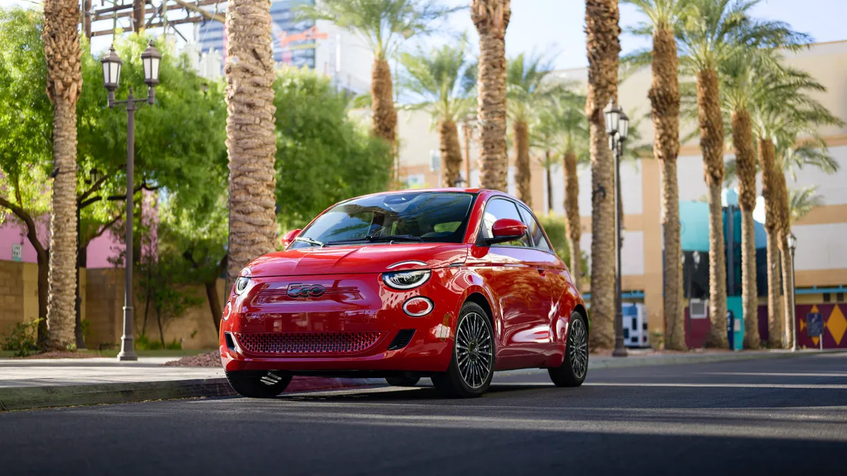 A  fully electric 2024 Fiat 500e painted red on the road with palm tress in the background in media photo provided by Stellantis.