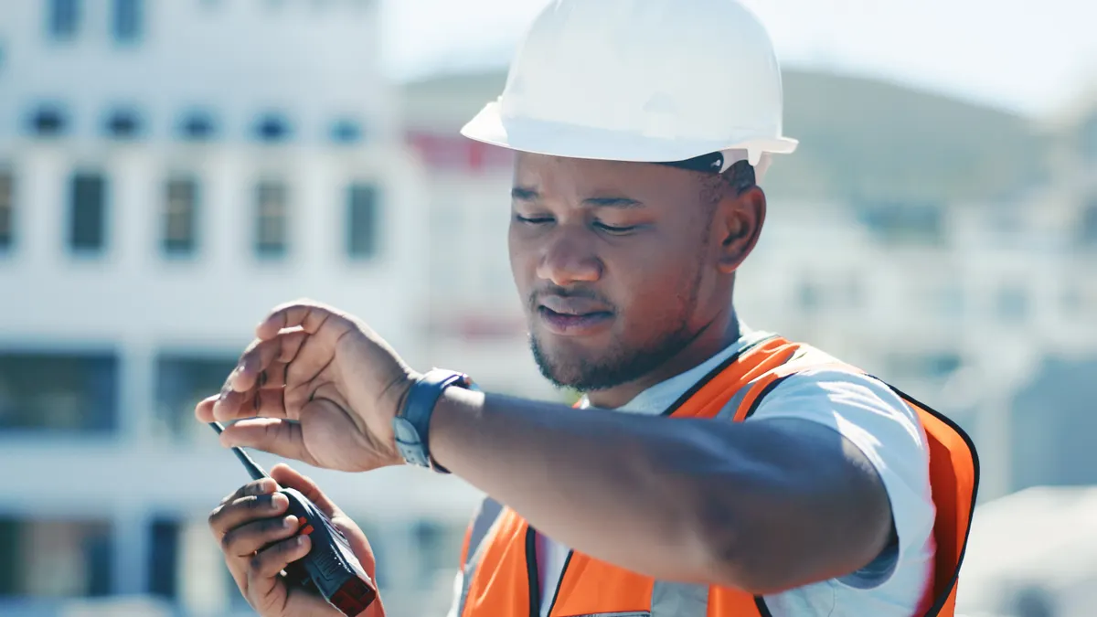 A construction supervisor looks at their wrist watch.