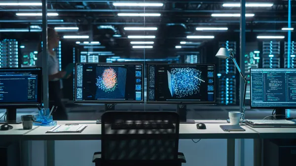 Two Digital Computer Screens with a Green Mock Up Chromakey in Modern Monitoring Office with someone walking in the background.