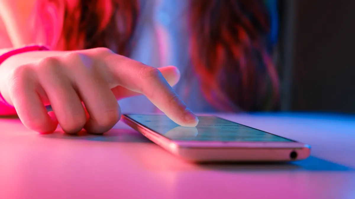 Hands of Teen Girl scrolling up photos Close-up at dark neon room.