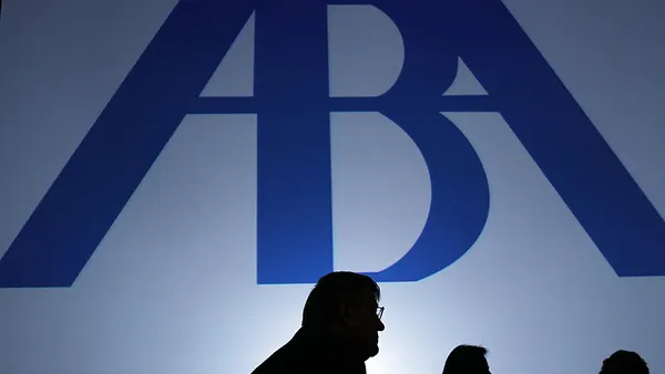 Man listening in silouette in front of lighted blue ABA banner.