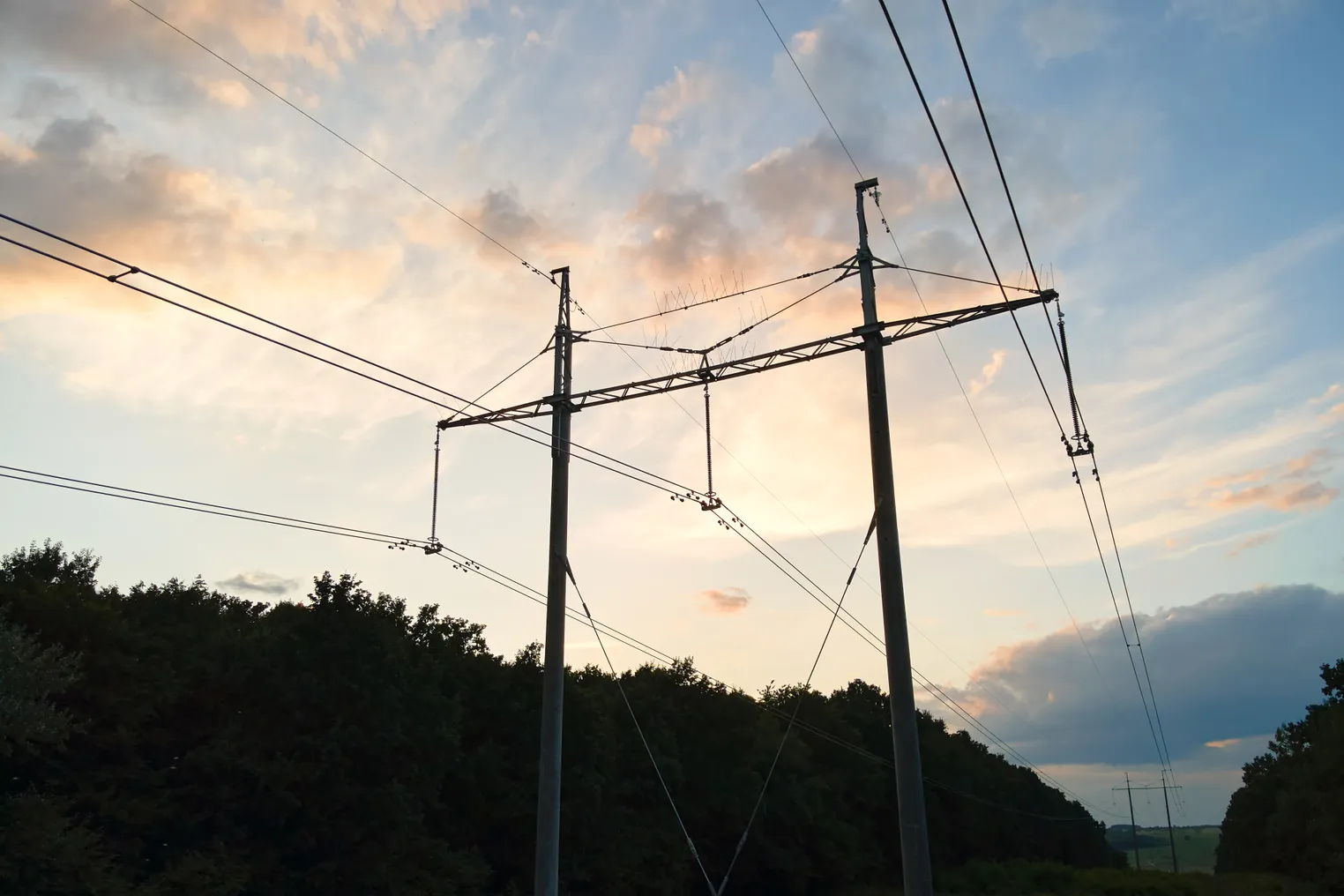 High voltage tower with electric power lines at sunset.