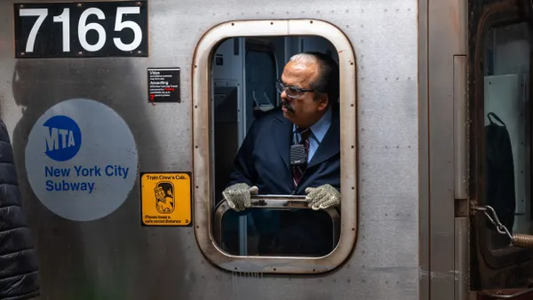 A man in the cab of a subway car looks out the window.