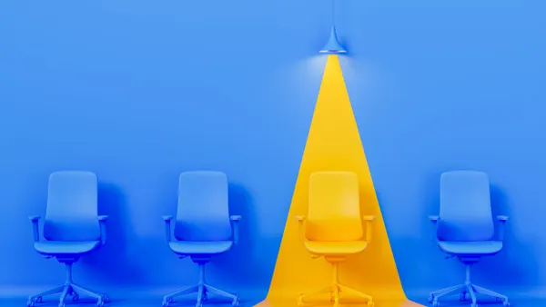 A photo illustration of a row of office chairs, with one illuminated by a spotlight.