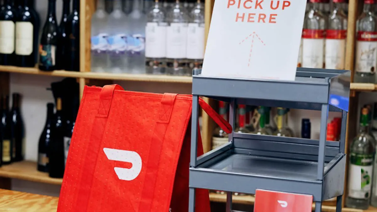 A delivery bag in front of bottles of alcohol in a store.