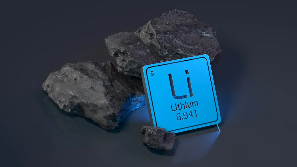 Chunks of lithium resting on a table with its a tab containing its periodic table number leaning against it.