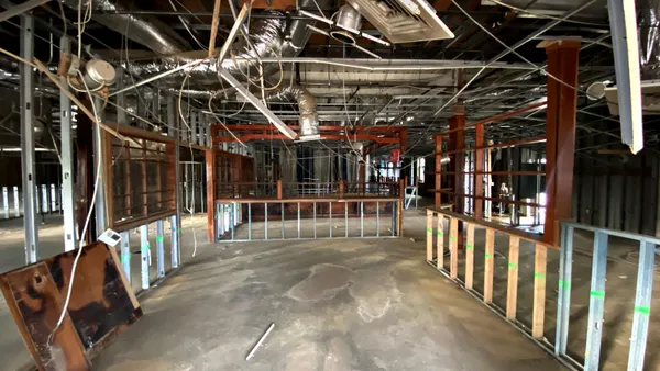 A photograph of a stripped out restaurant with wall studs and HVAC visible.