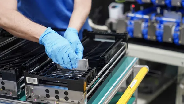 A person wearing gloves installing a device into an electric vehicle battery.