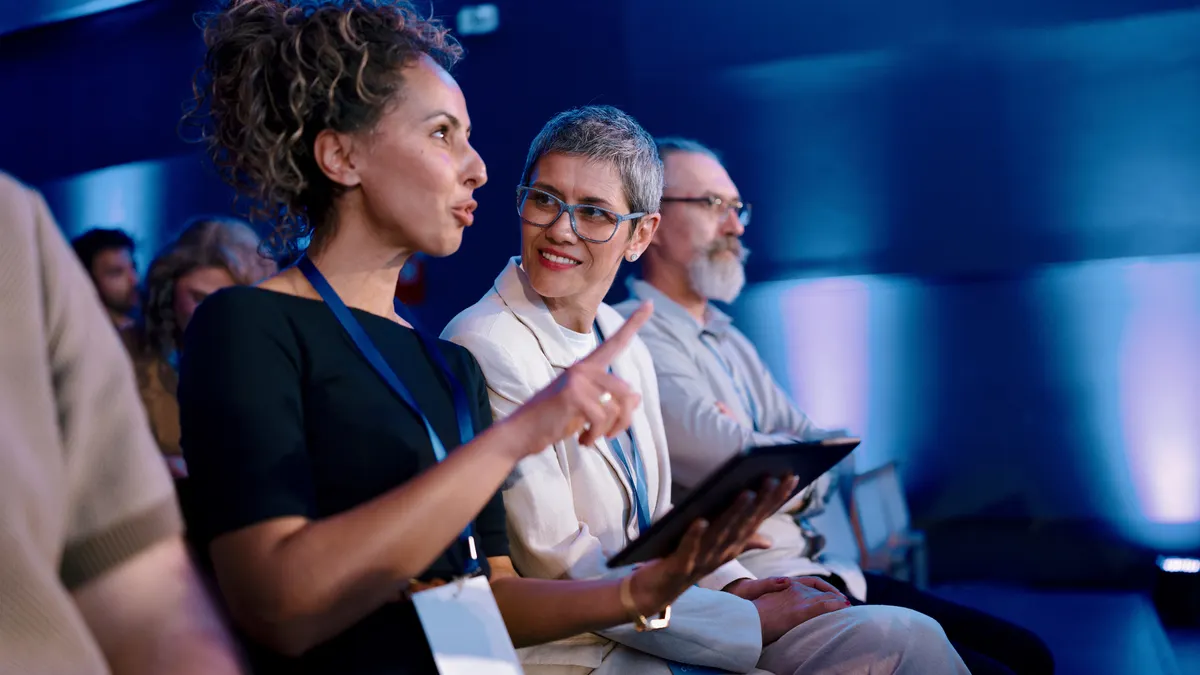 People at a conference look at a tablet.