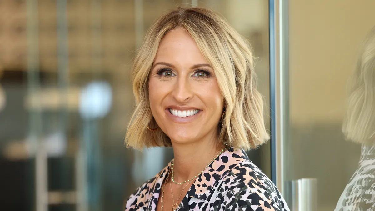 A CEO in a leopard=print dress standing in front of a glass door.