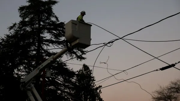 A utility worker makes repairs to electrical lines